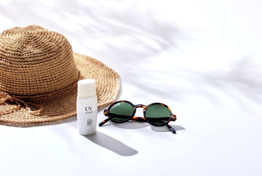 白い背景。麦わら帽子と50+の日焼け止めとサングラスがある画像