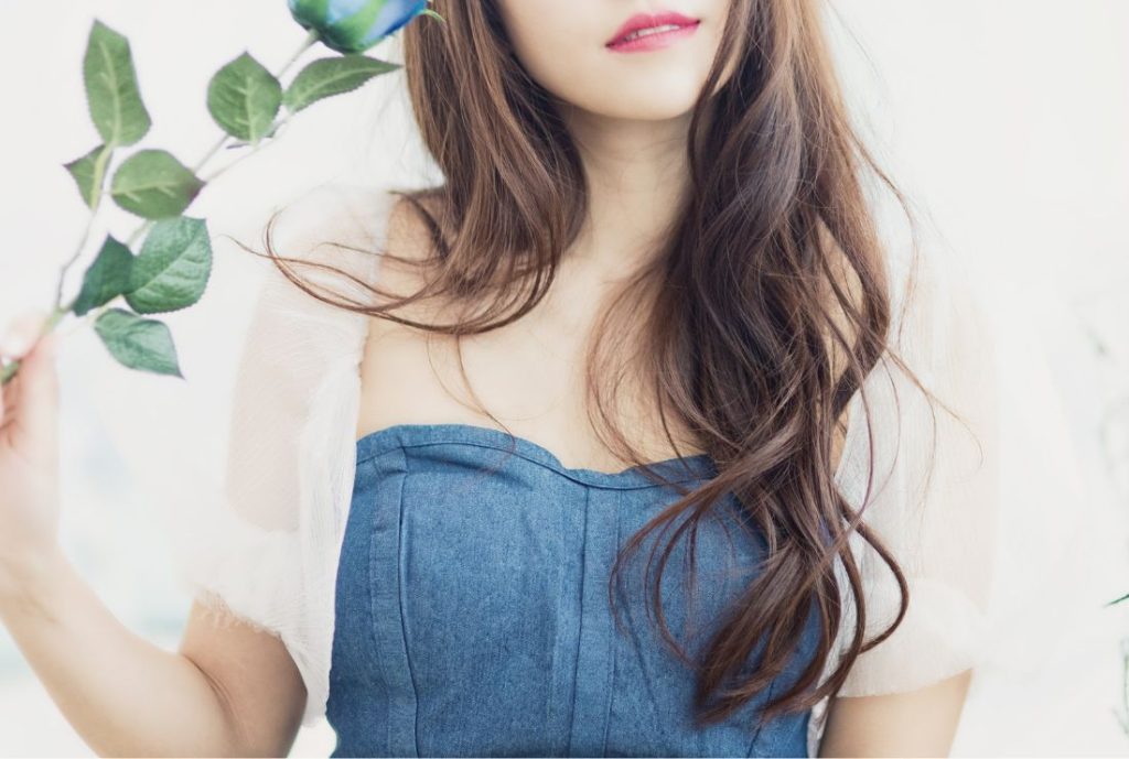 白い背景。女性が右手に観葉植物を持っている画像