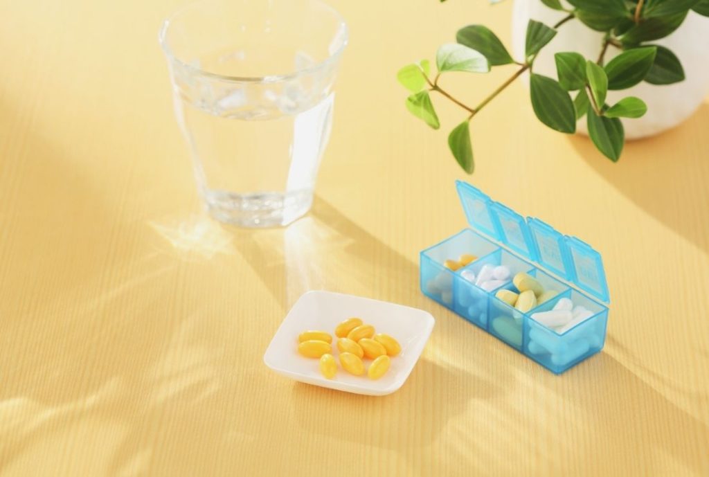 机の上に観葉植物と薬と水がある画像